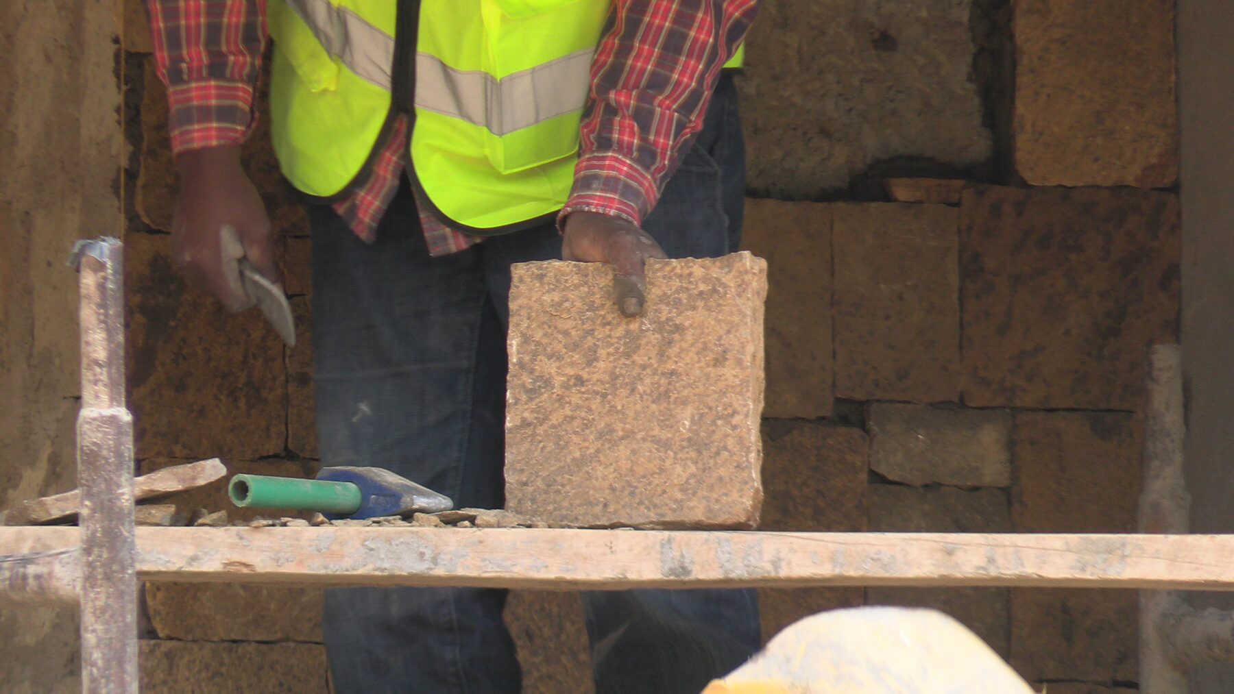 Mason cutting a stone block on site